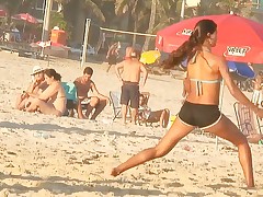 The turning above brunette above the beach is wearing the sport shorts and getting voyeured